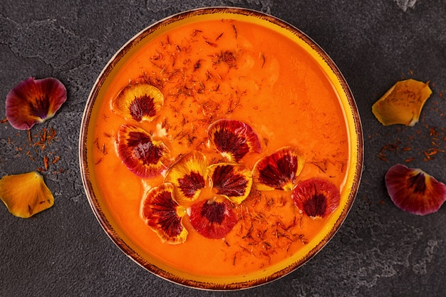 Smoothie or pumpkin / carrot soup with saffron and edible petals pansy flowers