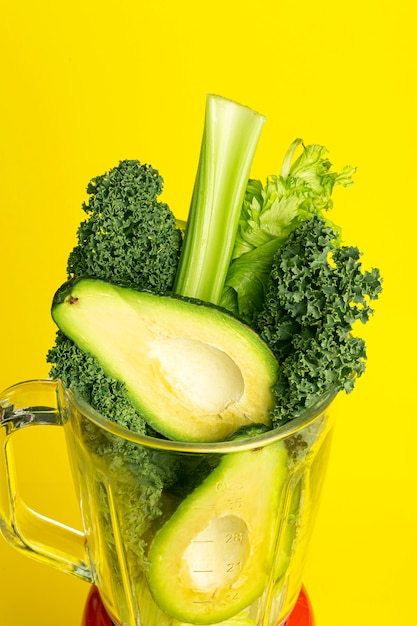 Smoothie recipe. green smoothie of vegetables (avocado, celery, cale salad, spinach) in a blender on a yellow background. vegan and healthy food detox concept