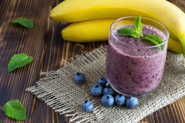 Smoothie van banaan en bosbessen op de bruine houten achtergrond