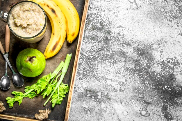 Photo smoothie with banana, pear and celery on rustic background