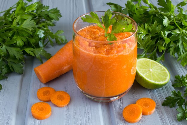 Smoothie with carrots on grey wood