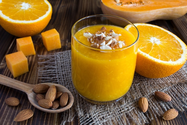 Smoothie with pumpkin, orange and almond on the rustic background