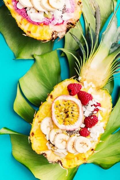 Smoothiekommen die in gesneden ananas op blauw worden gediend