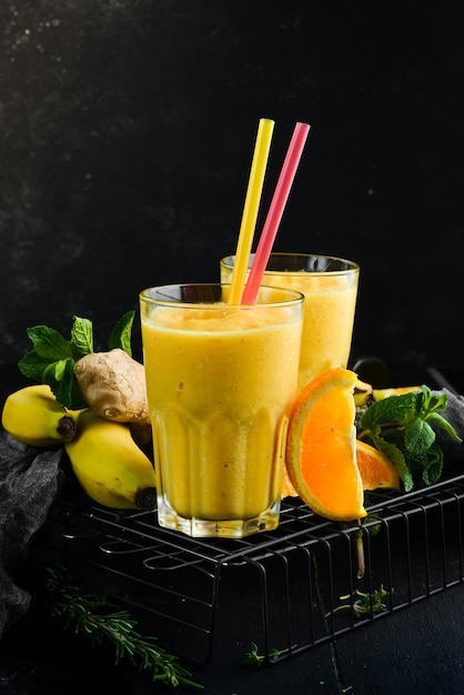 Smoothies Banaan, sinaasappel en gember smoothies Gezonde drankjes Bovenaanzicht Op een zwarte achtergrond