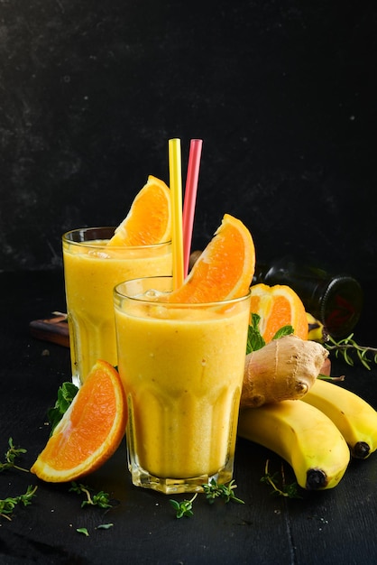 Smoothies Banana orange and ginger smoothies Healthy drinks Top view On a black background