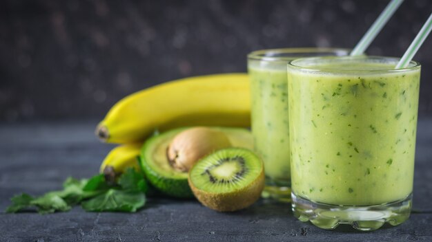 Smoothies from avocados, bananas, kiwi and herbs on a wooden table. Diet vegetarian food.