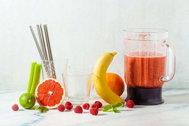 Smoothies in a glass blender bowl and ingredients on the table. Not disposable metal tubes. Healthly food.