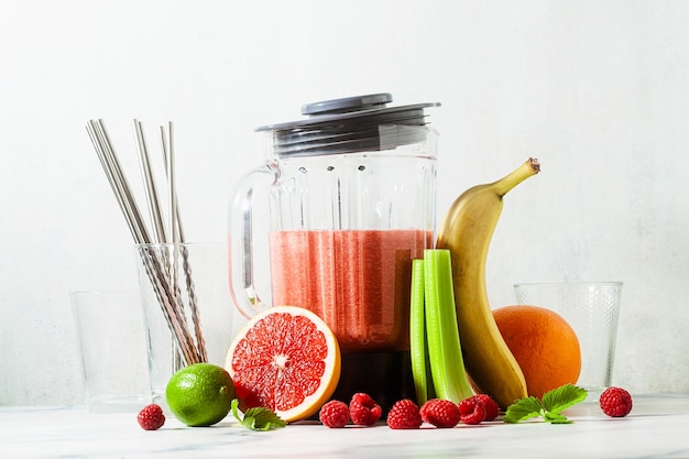 Smoothies in a glass blender bowl and ingredients on the table.