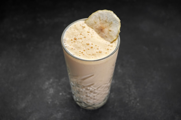 Smoothies of mango and banana in glass on a dark rustic background