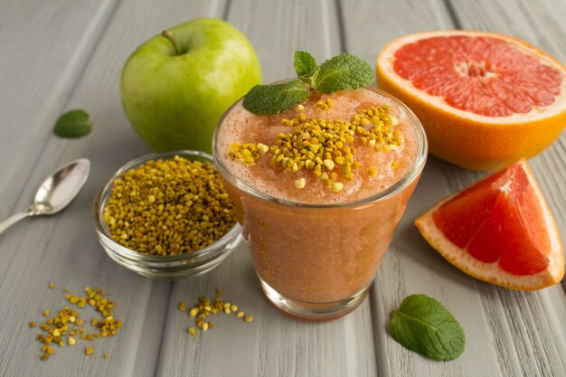 Smoothies met grapefruit, groene appel en bijenpollen op de grijze houten achtergrond