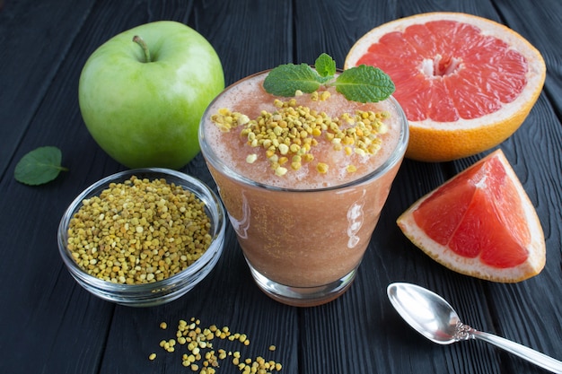 Smoothies met grapefruit, groene appel en bijenpollen op de zwarte houten oppervlak