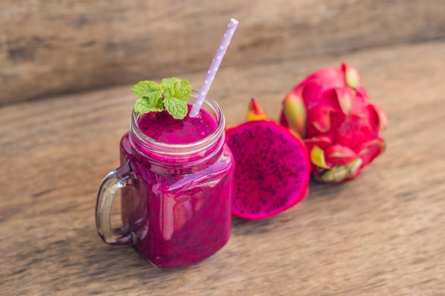 Smoothies of a red organic dragon fruit on an old wooden table