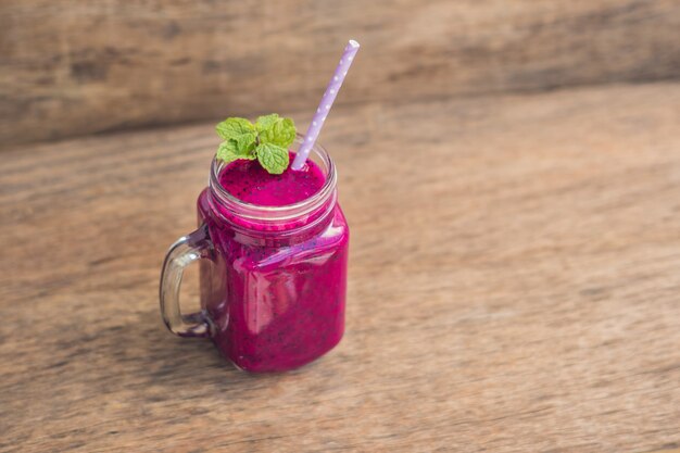 Smoothies of a red organic dragon fruit on an old wooden table