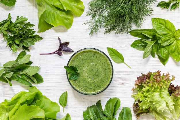 Smoothies and spring greens on a light wooden background.