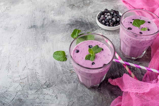 Smoothies van bosbessen en banaan in glazen en ingrediënten op een houten tafel