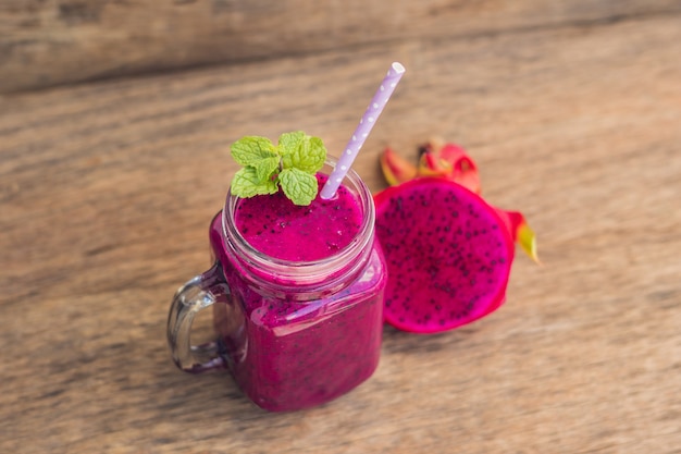 Smoothies van een rode biologische drakenfruit op een oude houten tafel