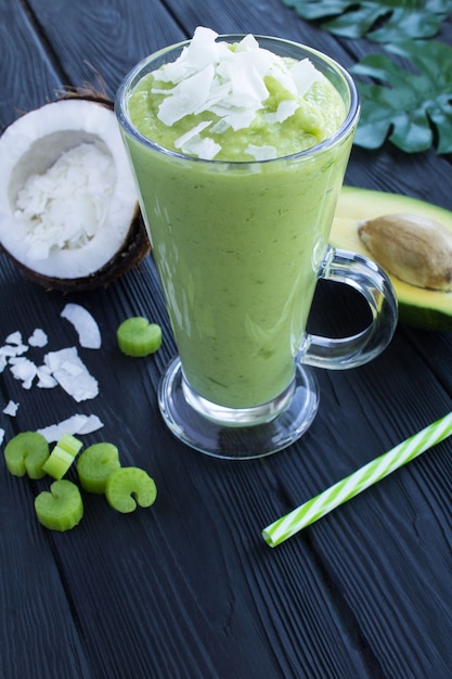 Smoothies with avocado, coconut milk and celery on the tropical table.