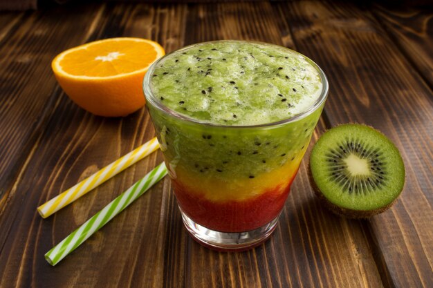 Smoothies with kiwi, orange and strawberry on the wood table