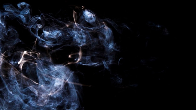 Photo smoothly blowing smoke against black background