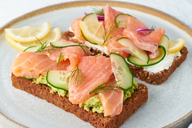 Smorrebrod - traditional Danish sandwiches. Black rye bread with salmon, cream cheese, cucumber, avocado on wood