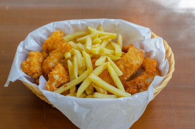 Snack Basket bevat friet, gebakken kipballetjes en uienringen geïsoleerd door houten achtergrond