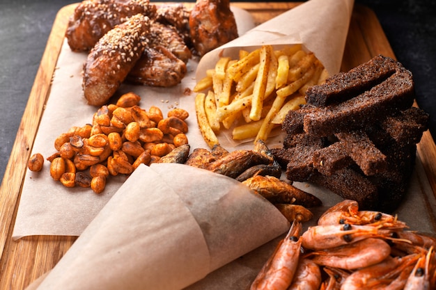 Snack to beer, on a wooden board. Shrimp. Fried fish. Fried peanuts. Fries. Chicken wings.Crunches. Croutons.