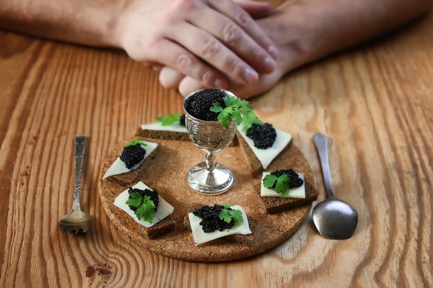 Snack black caviar on a wooden brown background