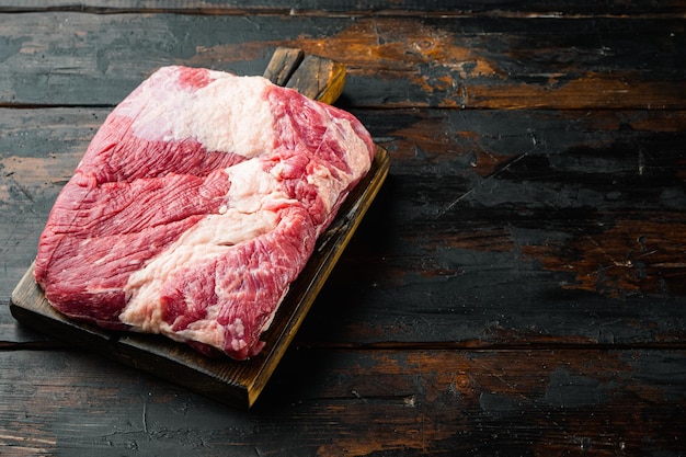 Snack tagliato a croce, set di carne di petto di manzo crudo, su vecchio sfondo di tavolo in legno scuro, con spazio per la copia del testo