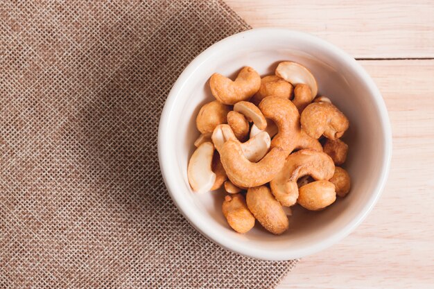 Snack Gezouten Cashewnoten in de kom op zak en houten tafel en houten lepel. snack in koffietijd