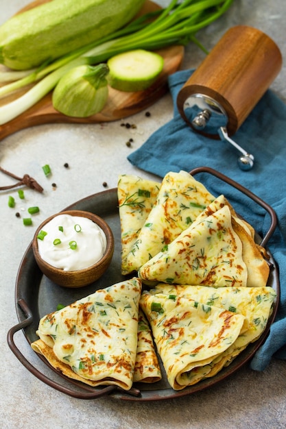 Snack or summer lunch Zucchini pancakes with herbs served with sour cream in a plate