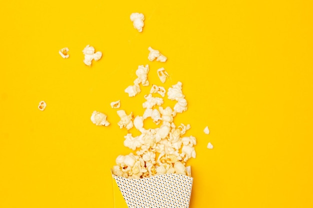 Snack van het kijken naar filmconcept Zoete popcorn drijft uit een papieren beker op gele achtergrond