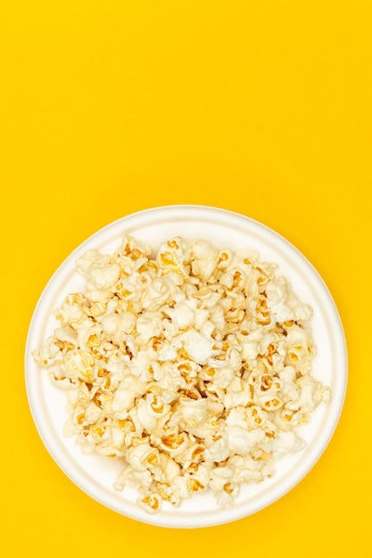 Snack van het kijken naar filmconcept Zoete popcorn in witte plaat op gele achtergrond