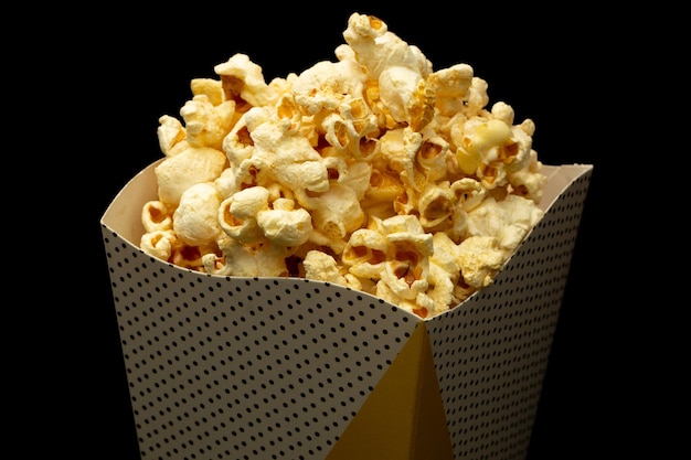 Snack di guardare il film concept popcorn dolce in tazza di carta su sfondo nero