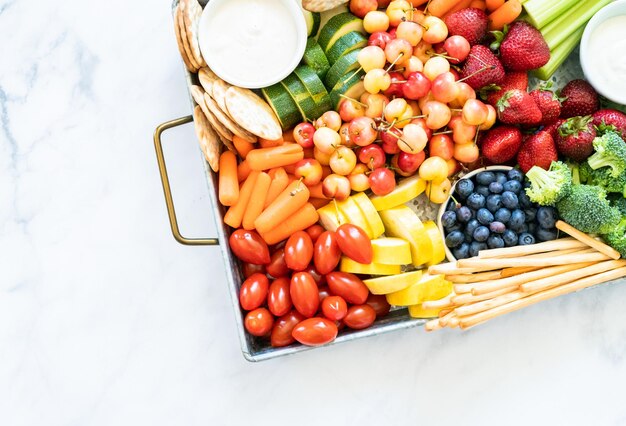 Snackbord met vers fruit, groenten, crackers en dipsauzen.