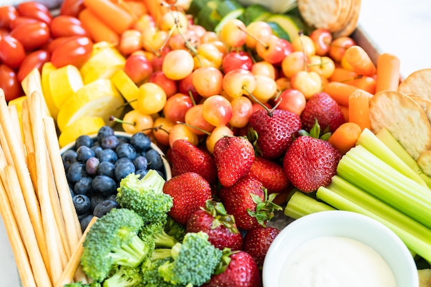 Snackbord met vers fruit, groenten, crackers en dipsauzen.