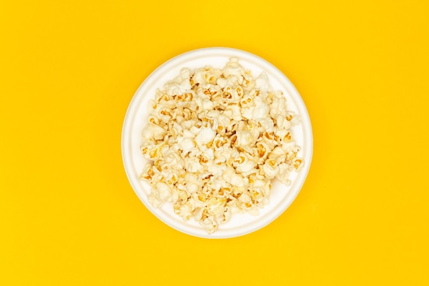 Snackconcept Zoete popcorn in witte plaat in het midden van gele achtergrond