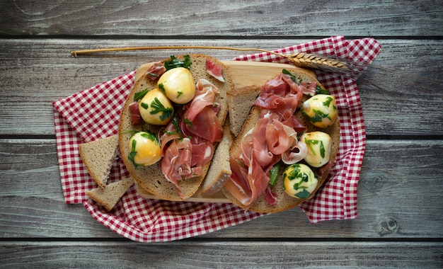 Snackhapje met volkorenbrood, rauwe ham en gerookte provolaballetjes in olie