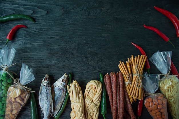 Snacks for beer, nuts and crackers. Beer snacks are packed in cellophane. Dark wooden background.