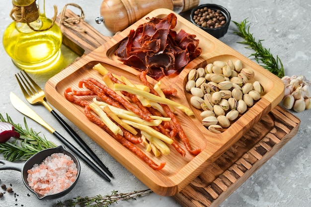 Snacks for beer pistachios cheese sausages and dried meat on a wooden plate rustic style