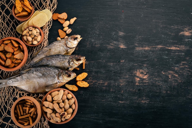 Snack per birra cracker salati patatine di pesce essiccate noci arachidi pistacchi su fondo di legno spazio libero per il testo vista dall'alto