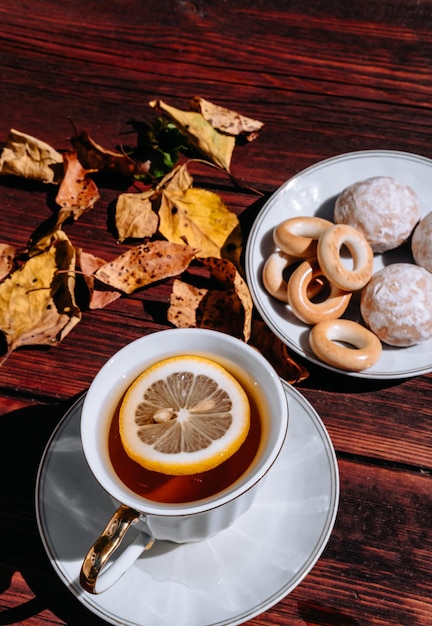 Snacks en snoep voor thee op een kleine witte schotel Herfstbladeren en thee in de natuur op een houten tafel