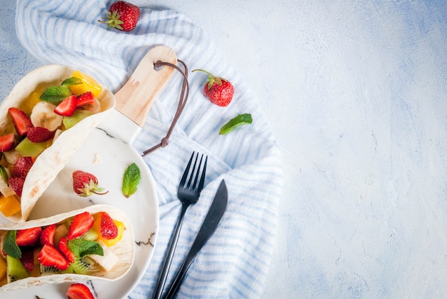  snacks. Food for a party. Fruit tacos with strawberries, mangoes, bananas, chocolate, mint