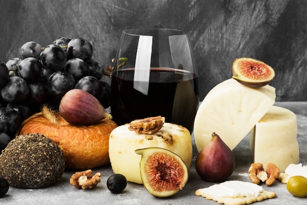 Snacks met wijn - verschillende soorten kaas, vijgen, noten, honing, druiven op een grijze achtergrond