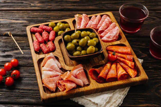 Foto snacks voor wijn op een houten bord menazhnitsa met worstolijven en kerstomaatjes