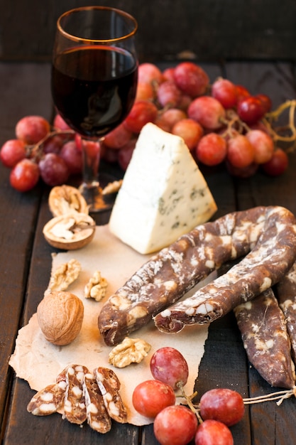 Snacks for wine, cheese with mold, pink grapes, walnuts and jerked dry sausage
