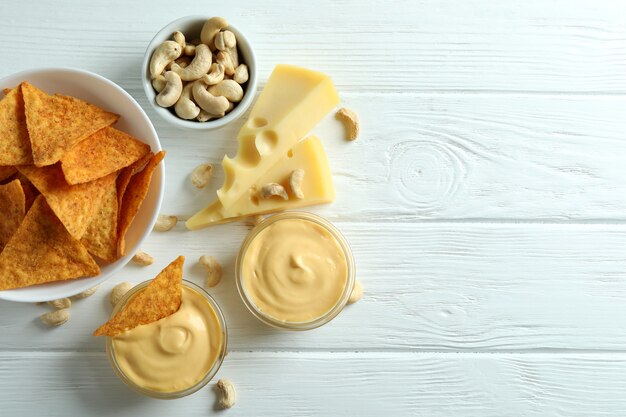 Snacks with cheese sauce on white wooden table