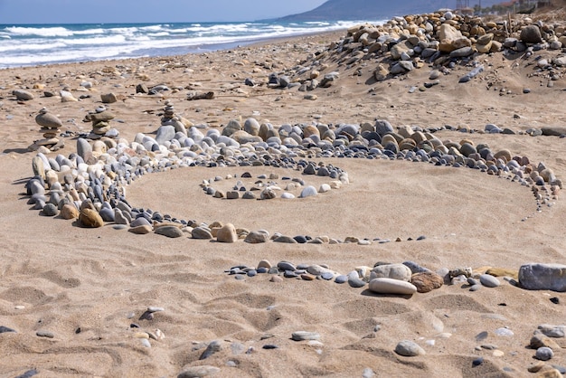 Snail made of stones in summer on the beach of Crete Greece