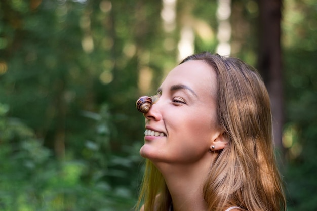 Snail sits on nose of woman Girl laughs and looks at clam Closeup portrait