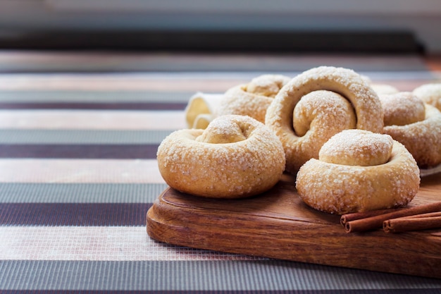 Snail sugar cookies with cinnamon on wooden board