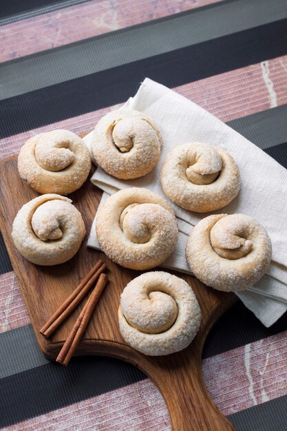 Snail sugar cookies with cinnamon on wooden board